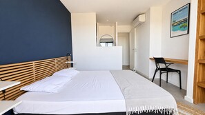 A bedroom with a bed, bedside table, and a desk with a chair.