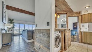 Una sala de estar moderna con un gran ventanal, un sofá gris y piso de madera.