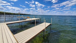Un muelle de madera que se adentra en aguas azules y cristalinas, con algunas sillas y mesas.