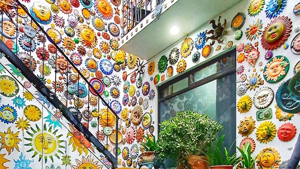 A staircase with a reflective floor and walls decorated with colorful sun and face motifs.