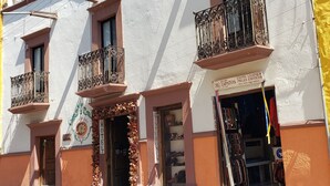 A hotel facade with balconies, a sign for 'Exotic Leather Pieles Exoticas', and a visible entrance.
