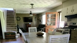 Una cocina amplia con una gran mesa de madera, un comedor y una escalera que lleva a un nivel superior.