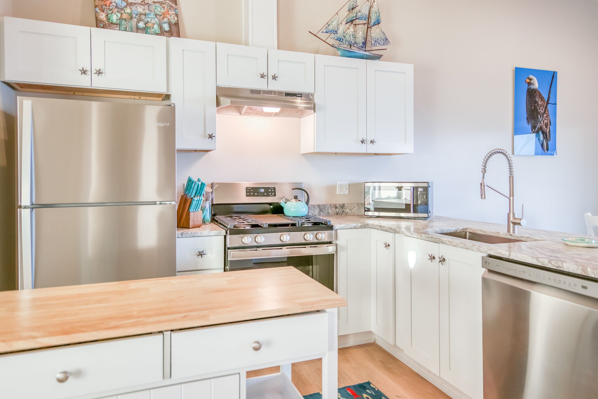 A modern kitchen with white cabinets, stainless steel appliances, and a wooden countertop.