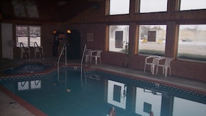 An indoor swimming pool with clear water, surrounded by a tiled deck and a brick border. There are two ladders for entry and exit, and a sign indicating no diving into the pool. - Motel6 Fond Du Lac, WI (Fond du Lac)