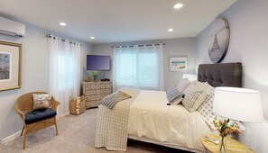 Un dormitorio con cama, cómoda, silla, televisión y ventana con cortinas.