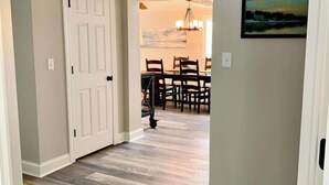 A hallway with a wooden floor, a white door, and a dining area with a table and chairs. - 2 Bedroom/Pet Friendly/short walk to Village (Skaneateles)