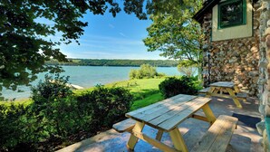 A lakeside picnic area with stone walls and wooden picnic tables. - Level Lakefront on Owasco Lake! Sleeps 14! (Auburn)