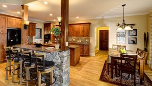 A spacious kitchen with wooden cabinets, a stone island, and bar stools.