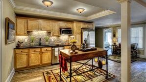A kitchen with wooden cabinets, a microwave, a refrigerator, and a dining area with a table and chairs.