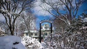 A snow-covered entrance to Thayer Park with a historic building in the background.