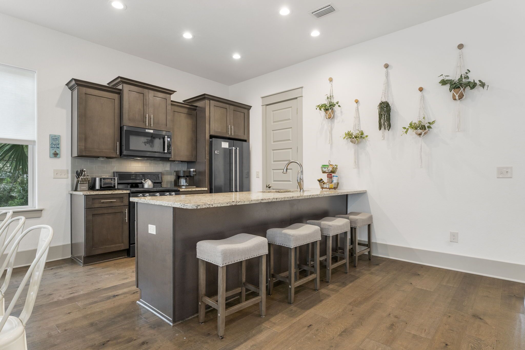 Una cocina moderna con armarios de madera, electrodomésticos de acero inoxidable y una isla central con taburetes de bar.