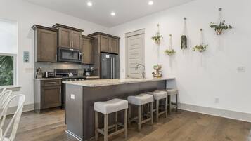 Una cocina moderna con armarios de madera, electrodomésticos de acero inoxidable y una isla central con taburetes de bar.