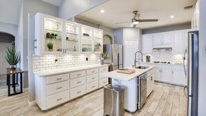 A modern kitchen with white cabinetry, a central island, stainless steel appliances, and a ceiling fan. - Lake Front Home with Pool, Dock, Views, Sports Court, & Beautiful Sunsets! (Lago Vista)