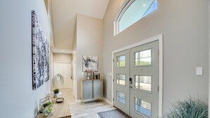 A modern hallway with a wooden console, a grey door with multiple windows, and a skylight. - Lake Front Home with Pool, Dock, Views, Sports Court, & Beautiful Sunsets! (Lago Vista)