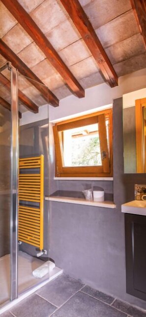 A bathroom with a glass shower enclosure, a wooden ceiling, a window, and a towel rack. - Il Borgo Incantato Dependance (Spoleto)
