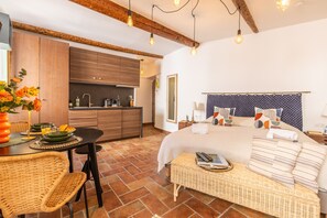 Une chambre à coucher avec un lit, une table de chevet et une vue sur la cuisine.