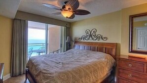 A hotel room with a bed, a ceiling fan, a dresser, and a view of the ocean. - Units at Atlantic Breeze by Elliott Beach Rentals (North Myrtle Beach)