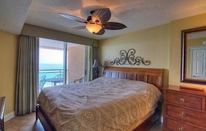 A hotel room with a bed, a ceiling fan, a dresser, and a view of the ocean. - Units at Atlantic Breeze by Elliott Beach Rentals (North Myrtle Beach)