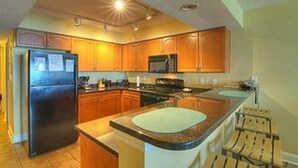 A modern kitchen with wooden cabinets, a built-in oven, and a large island with a sink. - Units at Atlantic Breeze by Elliott Beach Rentals (North Myrtle Beach)