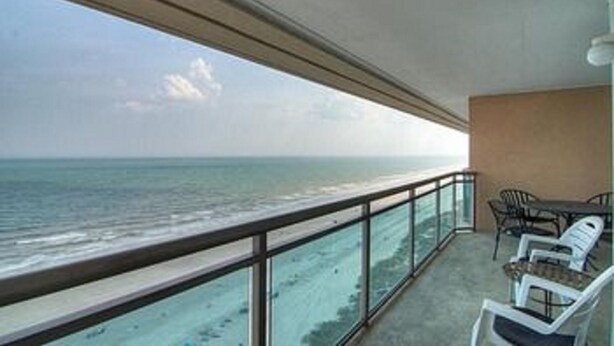 A balcony with a view of the ocean, a table, and two chairs. - Units at Atlantic Breeze by Elliott Beach Rentals (North Myrtle Beach)