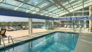 A swimming pool with a glass ceiling, lounge chairs, and a view of the landscape. - Units at Atlantic Breeze by Elliott Beach Rentals (North Myrtle Beach)