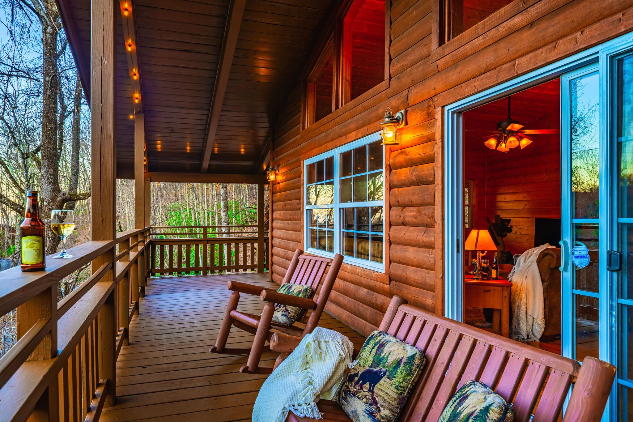A wooden cabin with a porch, a wooden bench, and a table with a lamp.