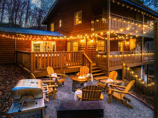 A log cabin with a deck, outdoor seating, and string lights.