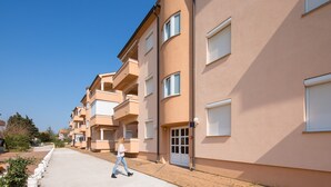 Eine Reihe moderner Wohngebäude mit Balkonen, ein gepflasterter Weg und ein strahlend blauer Himmel.