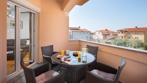 A balcony with wicker chairs, a glass table, and breakfast items.