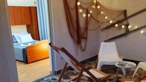 Une pièce avec un lit, une petite table et une chaise. On y trouve un escalier décoré de guirlandes lumineuses.
