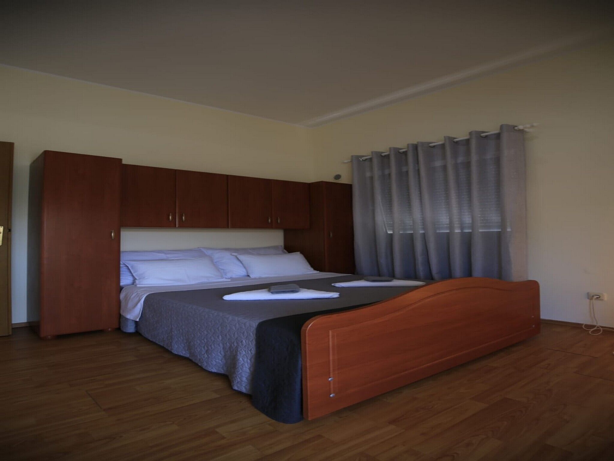 Une chambre à coucher avec un lit en bois, une armoire et une fenêtre avec des rideaux.