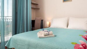 Ein Hotelzimmer mit Bett, Nachttisch, Lampe, einem Gemälde und Blick nach draußen.