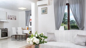 Ein modernes Wohnzimmer mit einem weißen Sofa, einem Glastisch und einem Essbereich mit Tisch und Stühlen.
