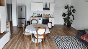 A compact kitchen with white cabinets, a dining table with chairs, and a large potted plant. - Apartments Melita - Two Bedroom Apartment with Balcony and Sea View (Zadar)