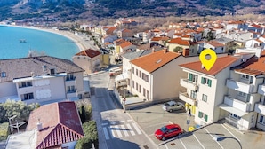 A coastal residential area with buildings, a beach, and a parking lot. - Nikolina B1 - Charming 2-Bedroom Haven for Four, Pet-Friendly with Parking (Baška)
