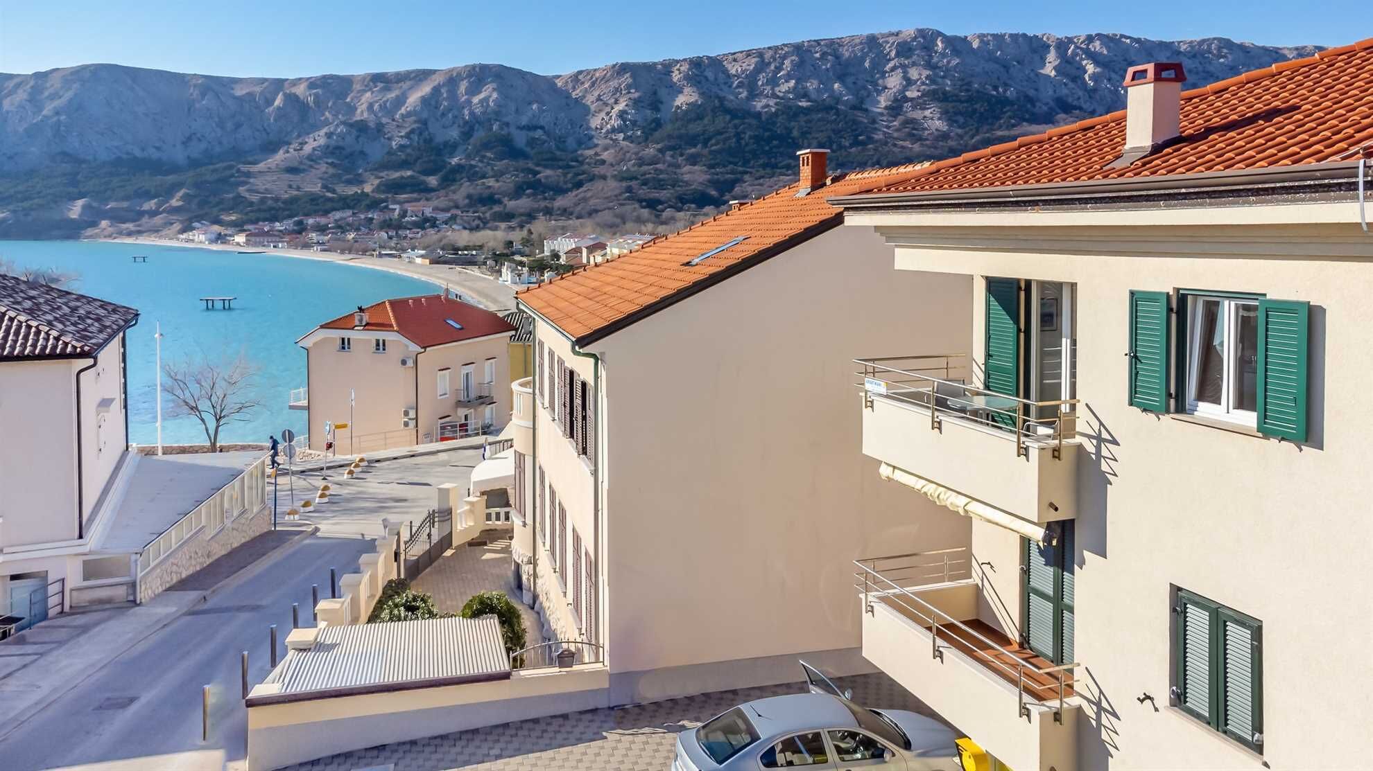 Un bâtiment situé sur la côte, doté d’un balcon donnant sur une plage et la mer.