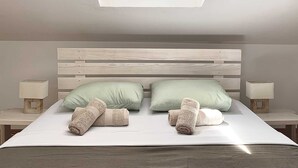 A bedroom with a skylight, a wooden headboard, two pillows, and two bedside tables with lamps. - Nikolina Bon Bon Happy Stay Center – Studio with Terrace & Sea view (Baška)