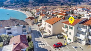 A coastal residential area with buildings, a beach, and a parking lot. - Nikolina Bon Bon Happy Stay Center – Studio with Terrace & Sea view (Baška)