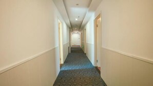 Un pasillo de hotel con alfombra estampada, paredes blancas y puertas a ambos lados.