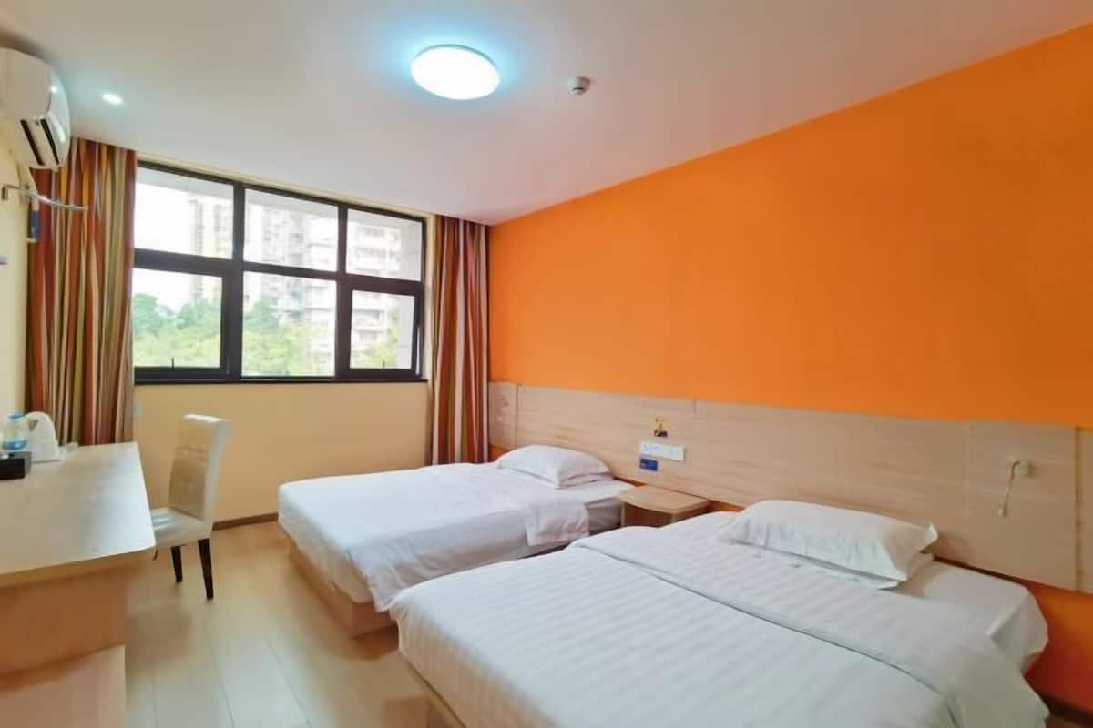 A hotel room with two beds, a desk, and a chair.