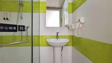 A bathroom with a sink, a mirror, a shower, and a towel rack.