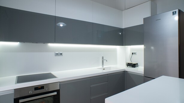 Eine moderne Küche mit einem Edelstahlkühlschrank, einem eingebauten Ofen und einer eleganten Arbeitsplatte.