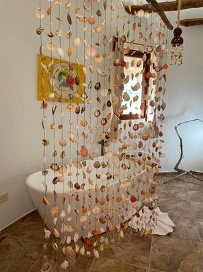 Ein Badezimmer mit einem einzigartigen Vorhangdesign aus Muscheln, einem Bild an der Wand und einem rustikalen Holzbalken.