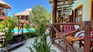 Un resort tropical con piscina, terraza de madera y edificios de techo de paja.