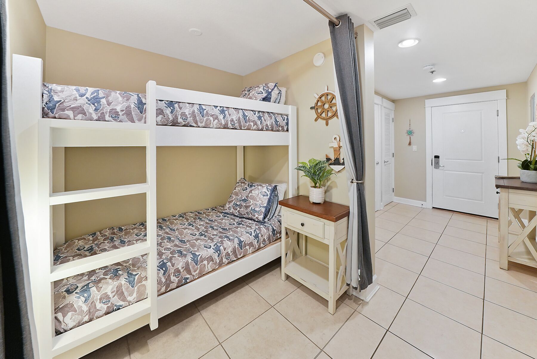 A bunk bed room with a desk and a potted plant.