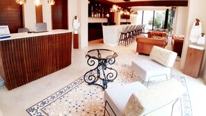 Eine moderne Hotellobby mit Rezeption, Bar, Sitzgelegenheiten und Blick ins Freie.