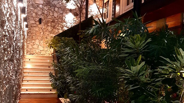 Eine Steintreppe führt zu einem Poolbereich mit umgebender Bepflanzung und einer Holzterrasse.