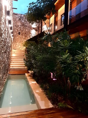 A stone staircase leading to a pool area with surrounding greenery and a wooden deck. - Casa Boutique Pasha (Mérida)