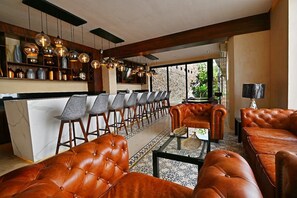 A modern interior with leather sofas, a bar area, and a view of greenery. - Casa Boutique Pasha (Mérida)
