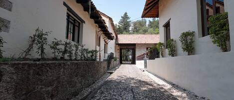 Un estrecho callejón adoquinado flanqueado por edificios con paredes blancas y balcones de madera.
